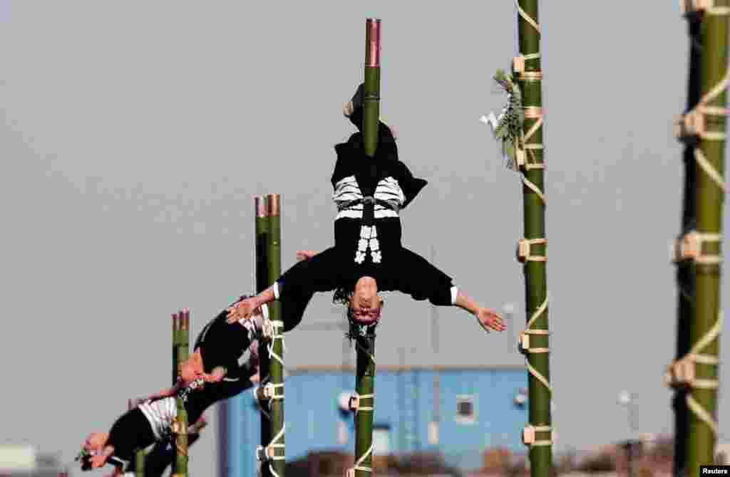 Members of the Edo Firemanship Preservation Association display their balancing skills atop bamboo ladders during Tokyo Fire Department's New Year's Fire review in Tokyo, Japan, Jan. 6, 2018.