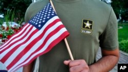 被美军解除兵役的22岁巴基斯坦籍新兵手举美国国旗接受采访。（2018年7月3日）