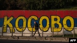 Пішохід проходить повз стінопис, пофарбований у кольори сербського прапора, з написом «Косово» в Белграді, 1 жовтня 2023 року. Фото AFP