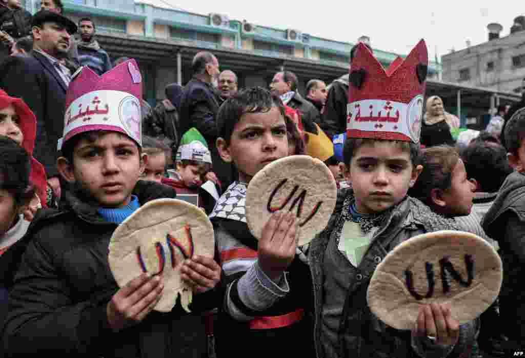 Palestinian children hold bread patties during a protest against aid cuts, outside the United Nations' offices in Khan Yunis in the southern Gaza Strip.