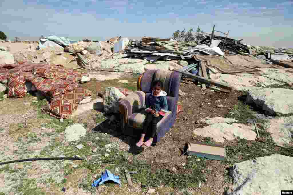 A Palestinian girl sits on a couch after Israel troops destroyed a structure in the village of Al-Eizariya, in the occupied West Bank, east of Jerusalem.