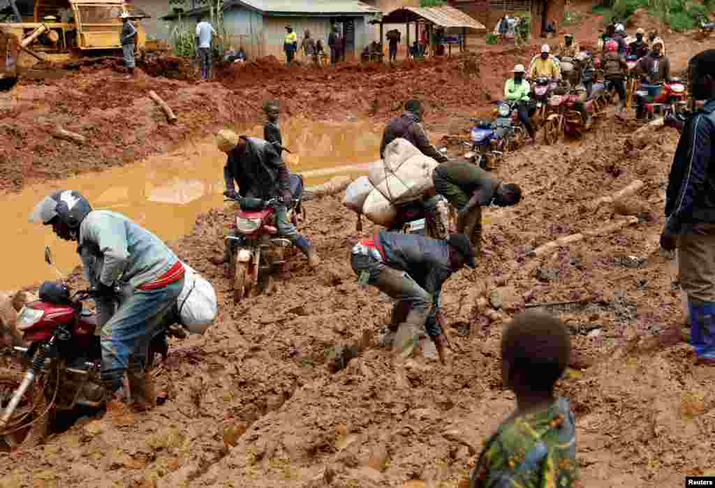 People and their motorbikes are stuck in the mud on a road near town of Mongbwalu in Ituri province, eastern Democratic Republic of Congo.