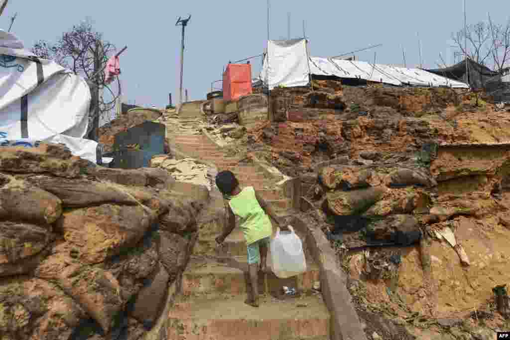 A Rohingya refugee child carries water to her temporary shelter days after a fire burnt down homes at a refugee camp in Ukhia, in the southeastern Cox&#39;s Bazar district, Bangladesh.
