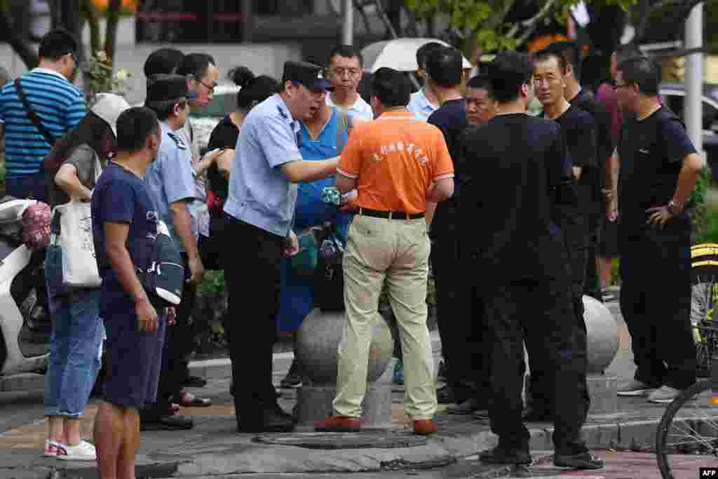 在北京的中国银监会附近,警察对中国P2P网络理财民间集资受害者讲话,旁边是保安人员(2018年8月6日)。受害者从中国各地到北京请愿维权。