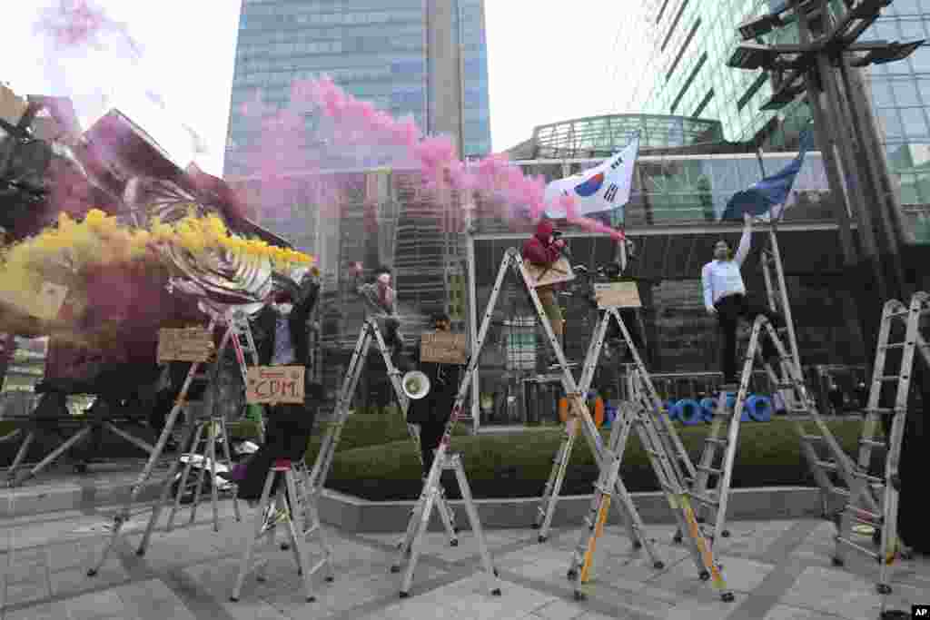 South Korean peace activists on the ladders light smoke bombs during a rally supporting Myanmar's democracy in Seoul.