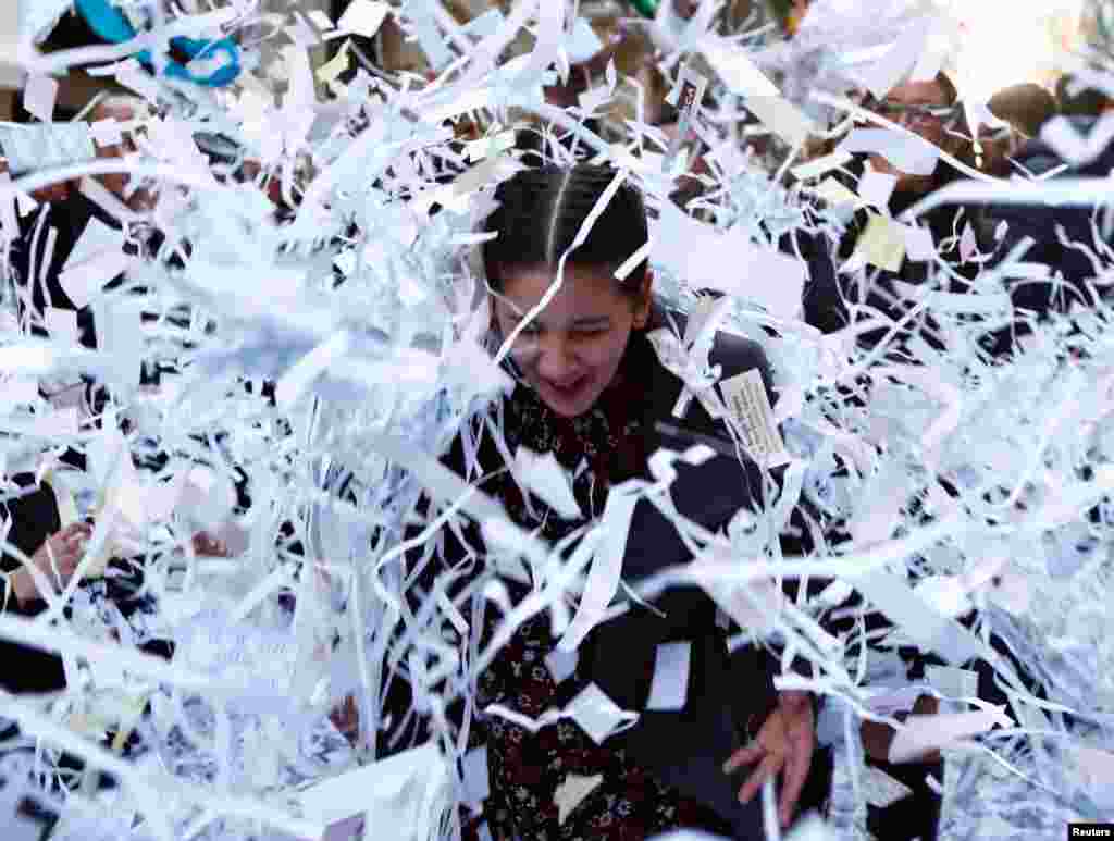 A woman reacts as she is hit by a bale of confetti during a band march at the feast marking the shipwreck in 60 A.D. of Saint Paul, Malta's patron saint, in Valletta, Malta, Jan. 27, 2018.