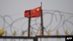 资料照：中国新疆喀什南部的一个铁丝网后的住宅区中飘扬的国旗。（2019年6月4日）