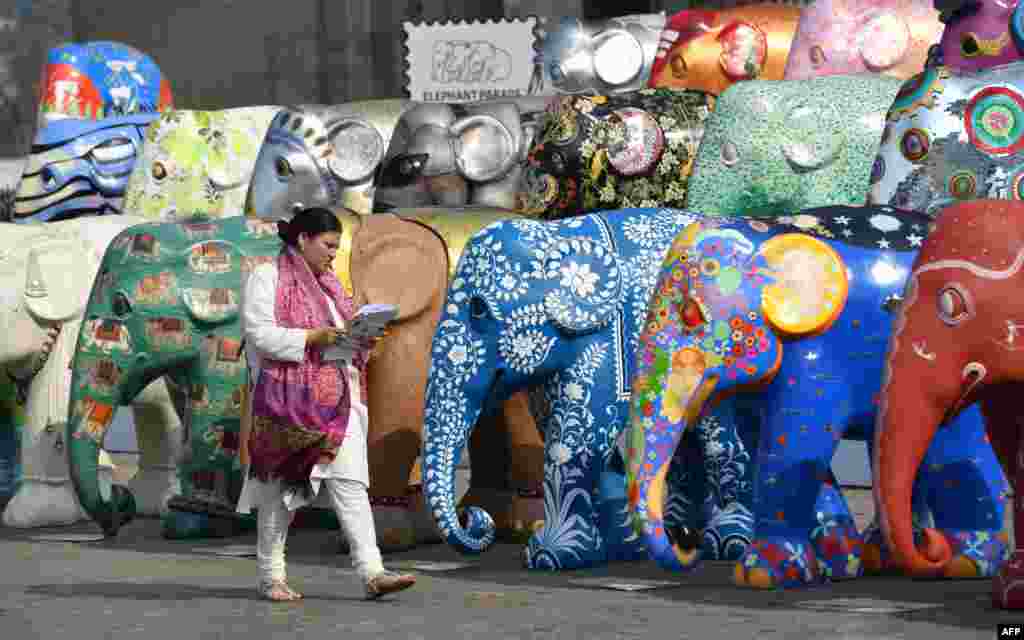 A woman walks among elephant sculptures displayed as part of the Elephant Parade India initiative in Mumbai, India.